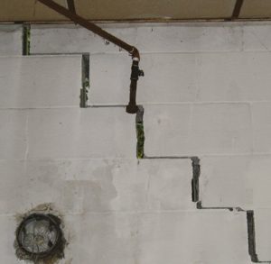 white cinderblock wall with stair step cracks
